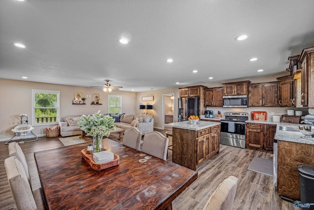 kitchen featuring recessed lighting, stainless steel appliances, open floor plan, a kitchen island, and wood finished floors