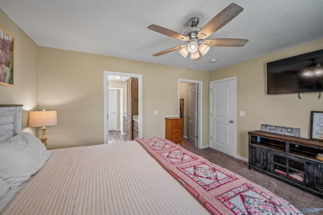 carpeted bedroom with ceiling fan, ensuite bathroom, and baseboards