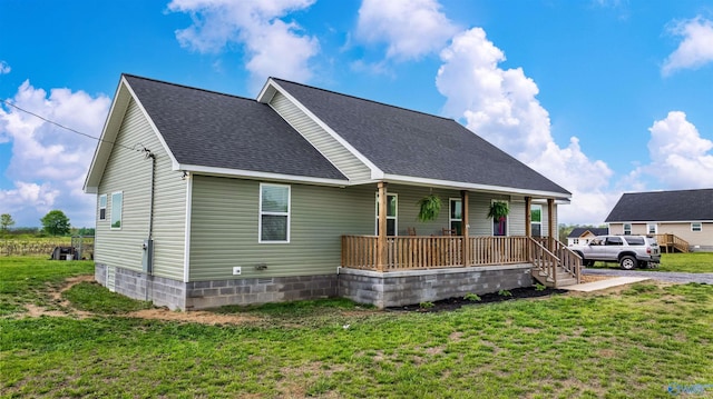 view of front of property with a front yard, a porch, a shingled roof, and crawl space