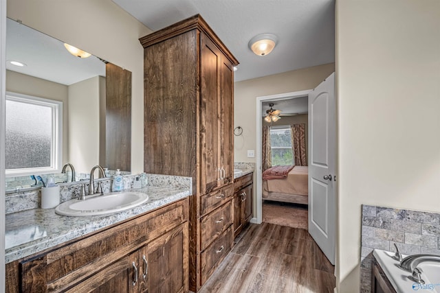 ensuite bathroom with wood finished floors, a tub, ensuite bathroom, and vanity