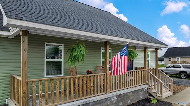 property entrance with covered porch and a shingled roof