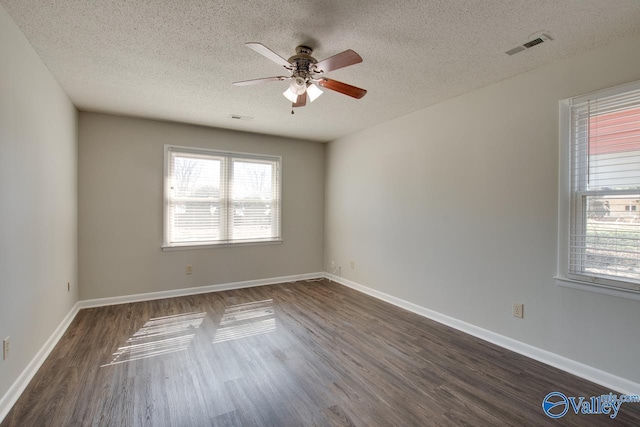 unfurnished room with dark wood-style floors, visible vents, and baseboards