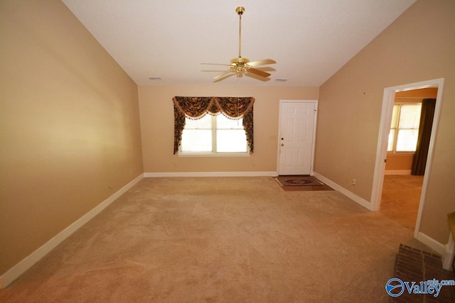 empty room with ceiling fan, light colored carpet, vaulted ceiling, and a wealth of natural light