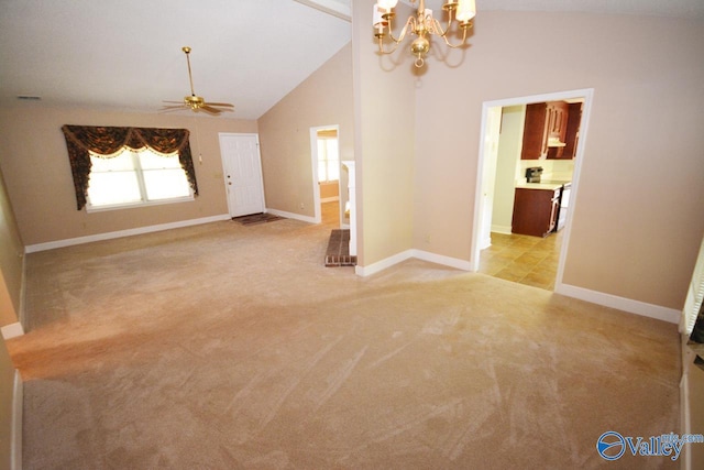 carpeted spare room featuring high vaulted ceiling and ceiling fan with notable chandelier