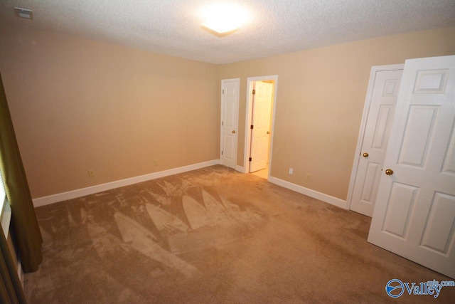 unfurnished bedroom with light colored carpet and a textured ceiling