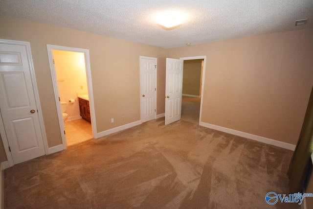 unfurnished bedroom featuring connected bathroom, carpet floors, and a textured ceiling