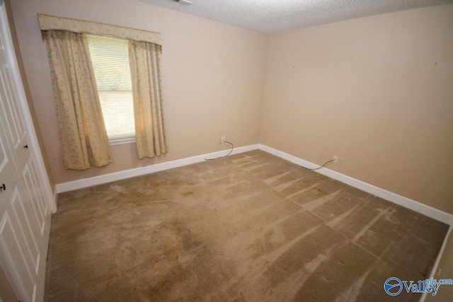 carpeted spare room with a textured ceiling