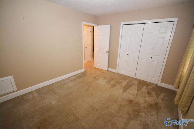 unfurnished bedroom featuring carpet flooring, a textured ceiling, and a closet