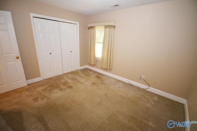 unfurnished bedroom with carpet floors, a textured ceiling, and a closet