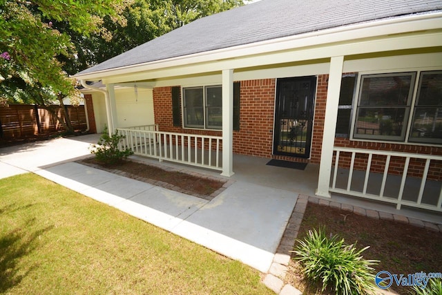 view of exterior entry with a yard and covered porch