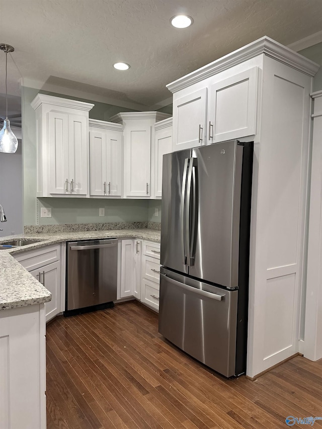 kitchen with dark wood finished floors, light stone countertops, stainless steel appliances, white cabinetry, and a sink