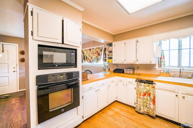 kitchen featuring white cabinetry, sink, black appliances, and light hardwood / wood-style floors