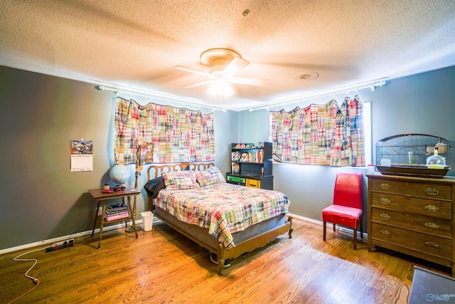 bedroom with a textured ceiling, hardwood / wood-style floors, and ceiling fan