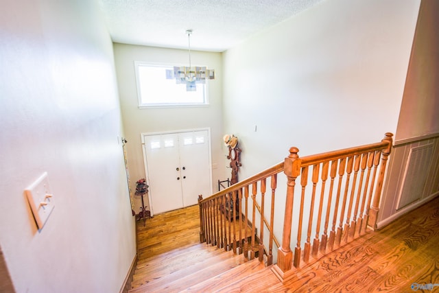 foyer entrance with a textured ceiling, an inviting chandelier, and hardwood / wood-style flooring