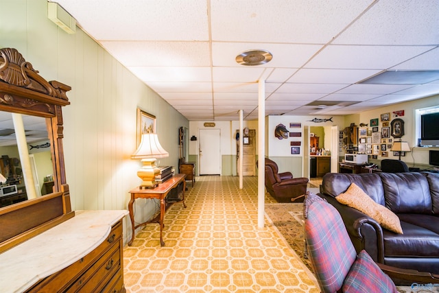 living room featuring a drop ceiling and light tile patterned floors