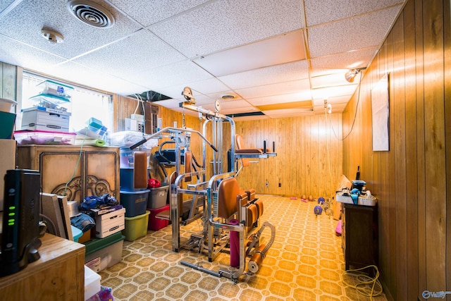 interior space featuring a drop ceiling, wood walls, and tile patterned flooring