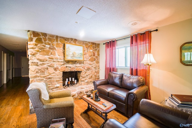 living room with a textured ceiling, a fireplace, and hardwood / wood-style flooring