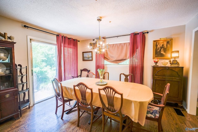 dining space with dark hardwood / wood-style flooring, a chandelier, and a textured ceiling