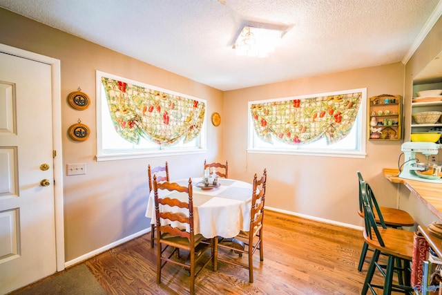 dining space featuring wood-type flooring, a textured ceiling, and a healthy amount of sunlight