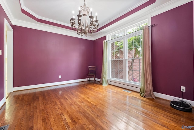 spare room with wood-type flooring, ornamental molding, a tray ceiling, and a chandelier