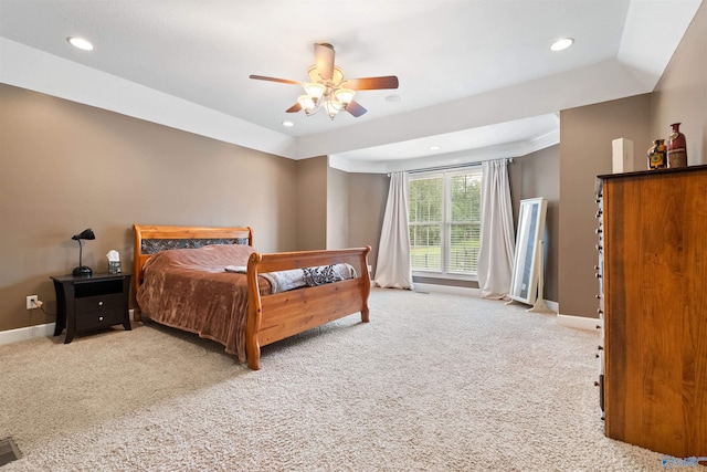 carpeted bedroom with ceiling fan and a raised ceiling