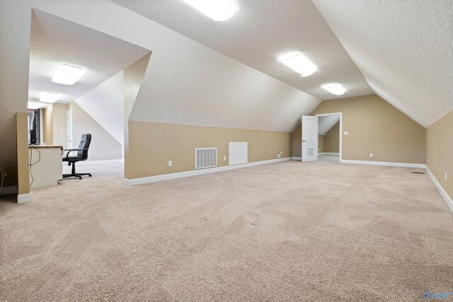 additional living space with light colored carpet, a textured ceiling, and lofted ceiling