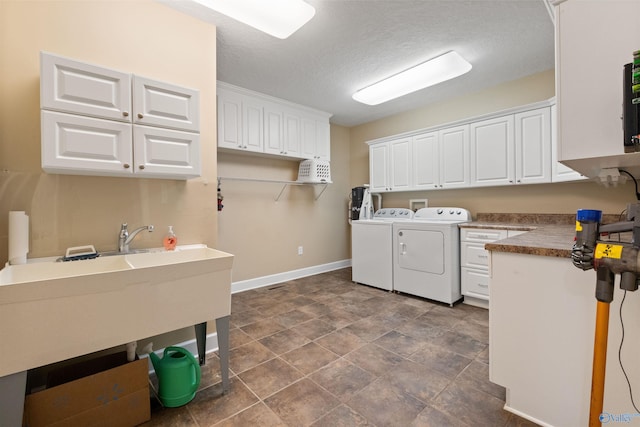 laundry area featuring washer and dryer, a textured ceiling, cabinets, and dark tile patterned flooring