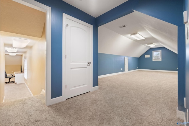 additional living space featuring light colored carpet and lofted ceiling