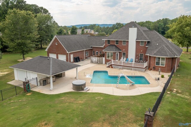 view of swimming pool with a wooden deck, a water slide, a yard, and a patio