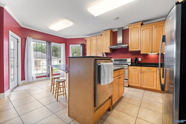 kitchen featuring appliances with stainless steel finishes, ornamental molding, wall chimney range hood, light tile patterned floors, and a kitchen island