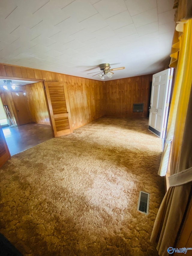 bonus room featuring ceiling fan, wood walls, and dark colored carpet