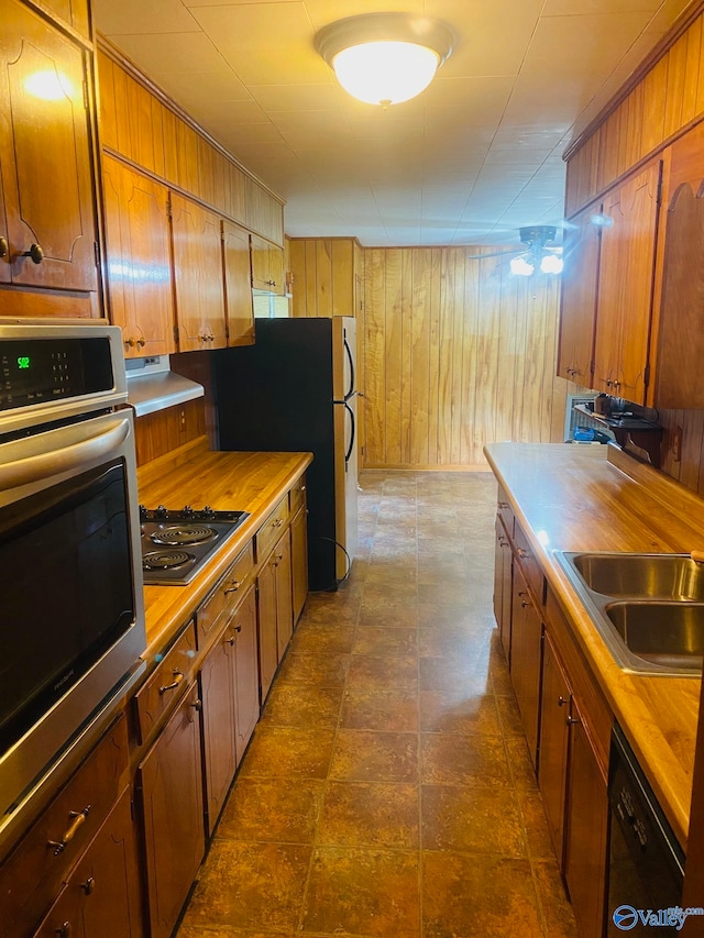 kitchen with wood walls, sink, wood counters, and black appliances