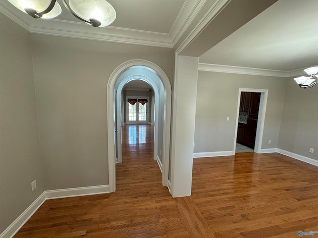 corridor with a notable chandelier, hardwood / wood-style flooring, and crown molding