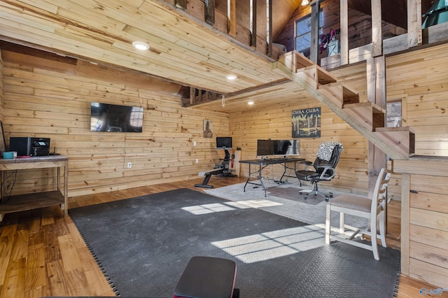 exercise room featuring hardwood / wood-style floors, a towering ceiling, and wooden walls