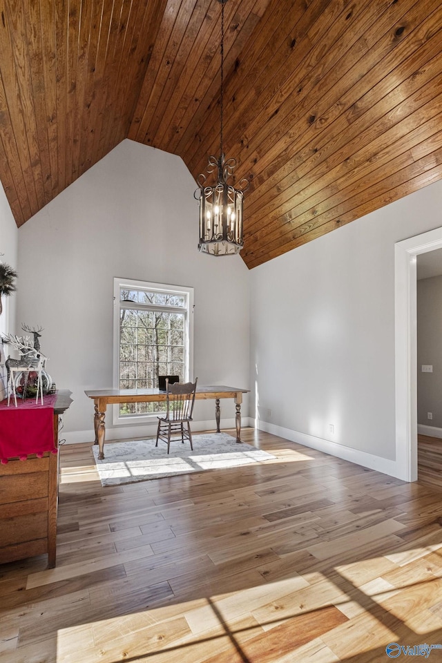 unfurnished dining area with light hardwood / wood-style floors, high vaulted ceiling, and an inviting chandelier