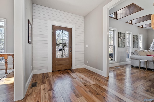 foyer featuring wooden walls, hardwood / wood-style floors, and a healthy amount of sunlight