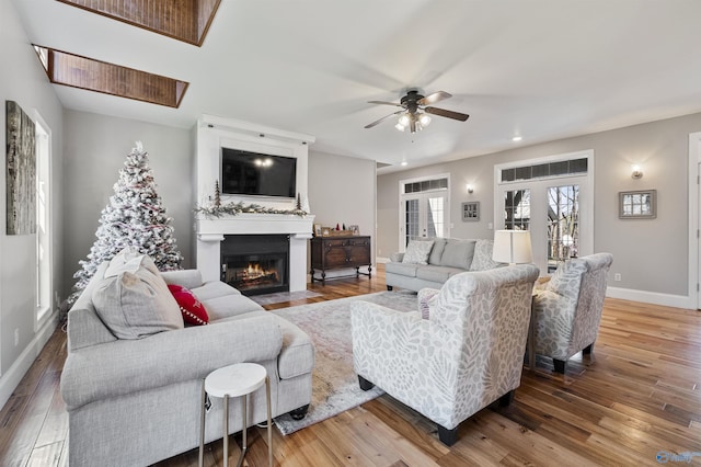 living room with hardwood / wood-style flooring, ceiling fan, a fireplace, and french doors