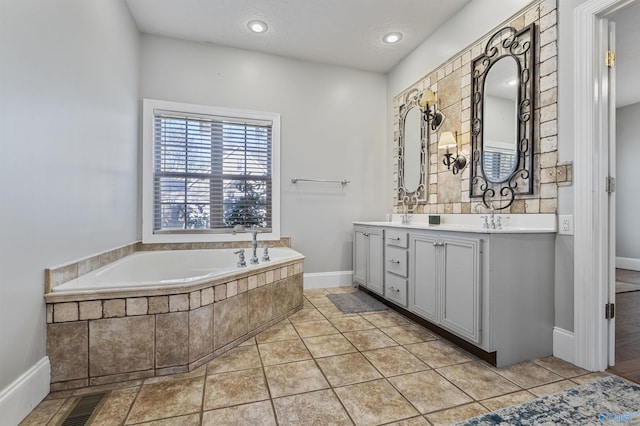 bathroom with tile patterned floors, tiled tub, and vanity