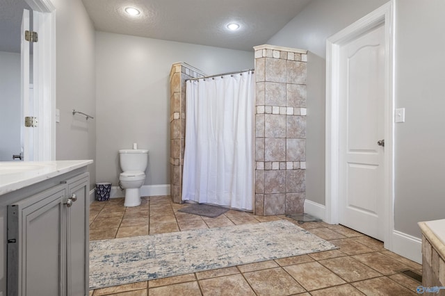 bathroom with a shower with curtain, vanity, a textured ceiling, and toilet