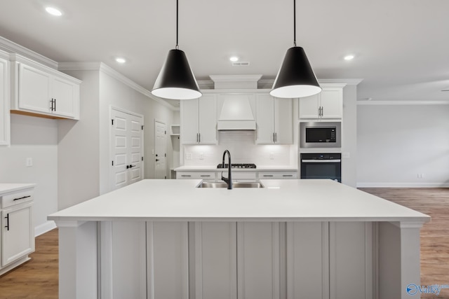 kitchen with built in microwave, decorative light fixtures, oven, and a center island with sink