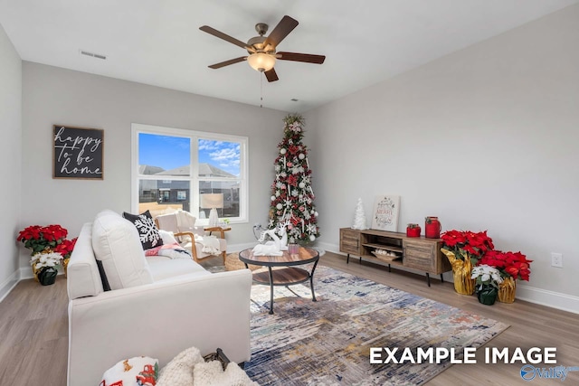 living room featuring visible vents, ceiling fan, baseboards, and wood finished floors