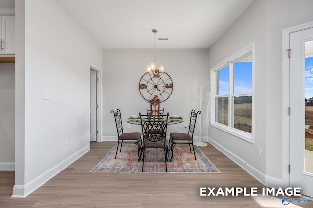 dining space featuring light wood-style floors, visible vents, baseboards, and an inviting chandelier