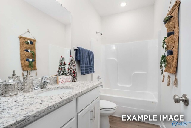 bathroom featuring wood finished floors, bathing tub / shower combination, vanity, and toilet