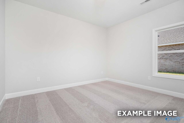 carpeted spare room featuring visible vents and baseboards