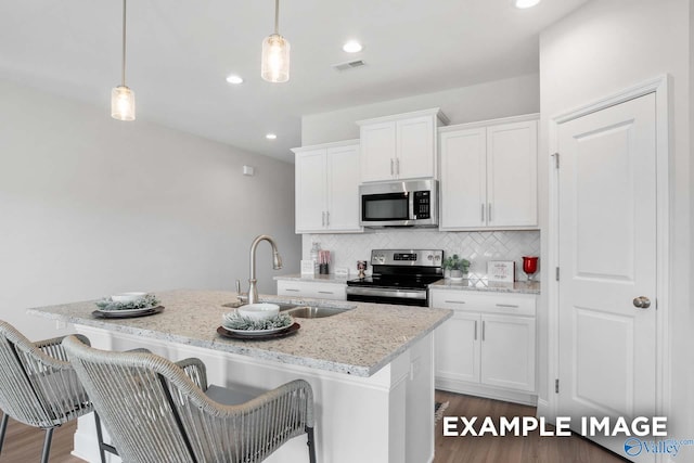 kitchen with visible vents, decorative backsplash, a kitchen island with sink, stainless steel appliances, and a sink