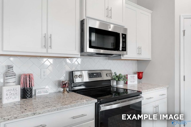 kitchen featuring appliances with stainless steel finishes, white cabinetry, backsplash, and light stone countertops