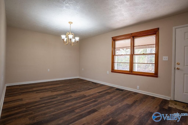 unfurnished room featuring a chandelier, a textured ceiling, and dark hardwood / wood-style floors