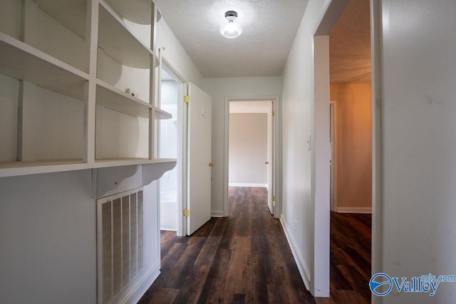 corridor with dark hardwood / wood-style flooring and a textured ceiling