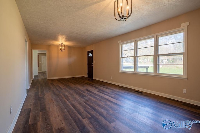 unfurnished room with dark hardwood / wood-style flooring, a textured ceiling, and an inviting chandelier