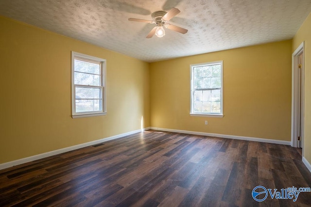 empty room featuring dark hardwood / wood-style flooring, a textured ceiling, a wealth of natural light, and ceiling fan